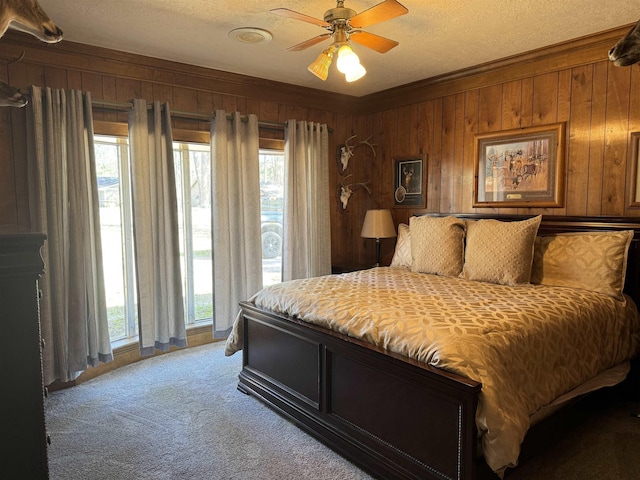 bedroom with light carpet, a ceiling fan, ornamental molding, a textured ceiling, and wood walls