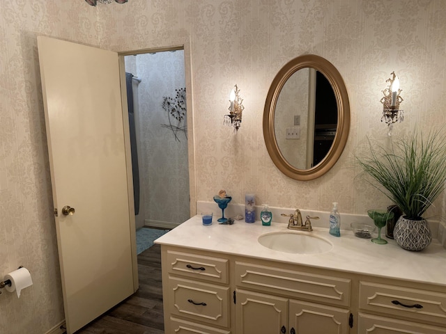 bathroom with wallpapered walls, wood finished floors, and vanity