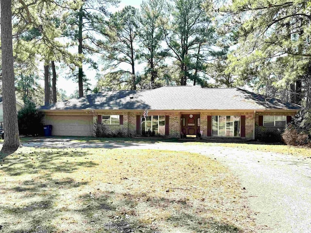 single story home with a front yard, brick siding, and an attached garage