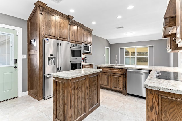 kitchen featuring light stone counters, stainless steel appliances, sink, a center island, and light tile patterned flooring