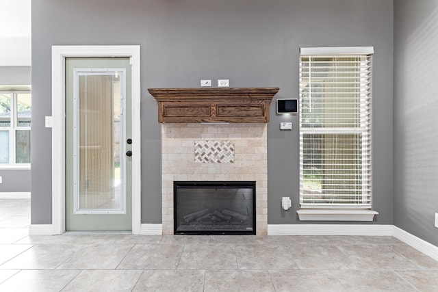 unfurnished living room featuring light tile patterned flooring, a wealth of natural light, and a tiled fireplace