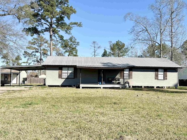 rear view of house with metal roof, an attached carport, and a yard