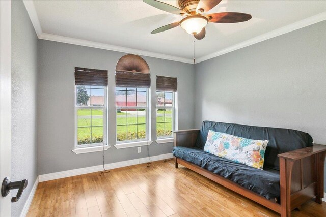 living area with ceiling fan, wood-type flooring, and ornamental molding