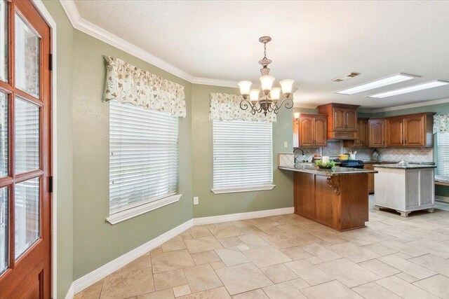 kitchen featuring hanging light fixtures, a notable chandelier, kitchen peninsula, decorative backsplash, and ornamental molding