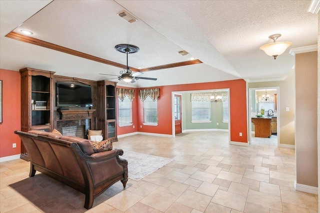 living room with a textured ceiling, ceiling fan with notable chandelier, a tray ceiling, and ornamental molding