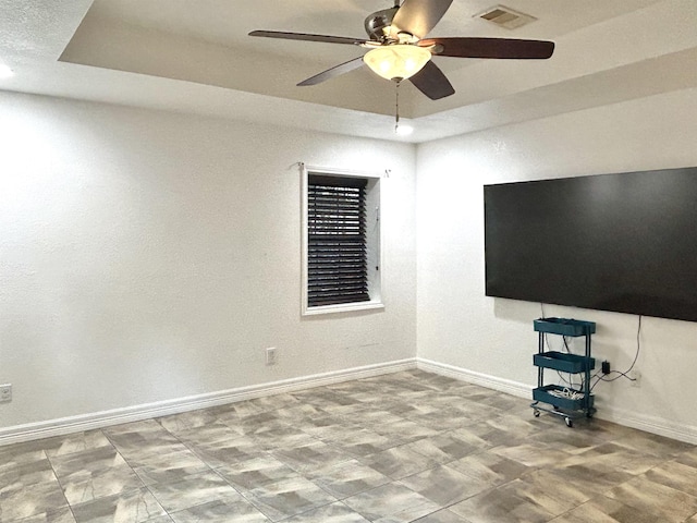 unfurnished living room featuring a raised ceiling and ceiling fan