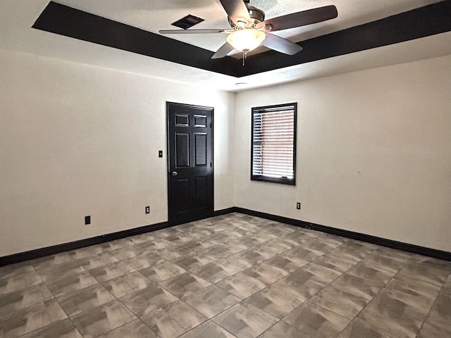 spare room featuring ceiling fan and a raised ceiling