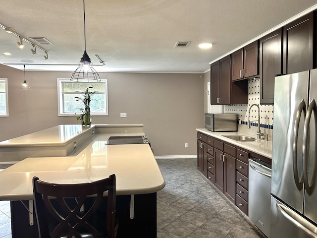 kitchen with a breakfast bar, sink, hanging light fixtures, and appliances with stainless steel finishes