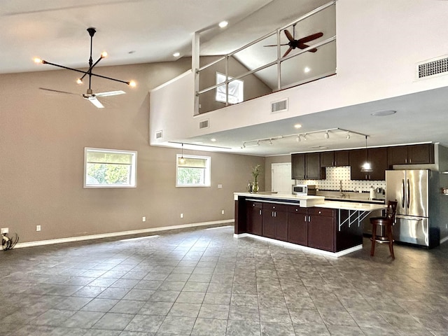 kitchen featuring a center island, backsplash, stainless steel fridge, and hanging light fixtures