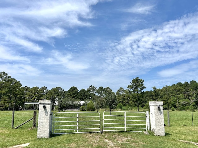 view of gate featuring a rural view and a lawn