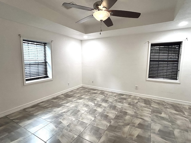 spare room with tile patterned flooring, a tray ceiling, and ceiling fan