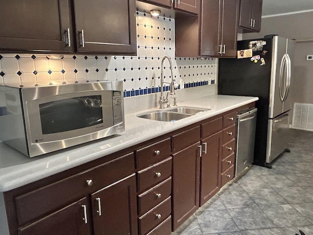 kitchen featuring tasteful backsplash, sink, stainless steel appliances, and dark brown cabinets