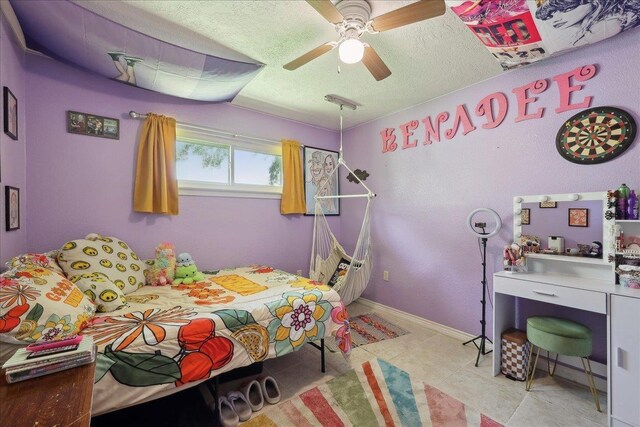 233 Spooner St, Orange, TX 77630 - bedroom featuring light tile patterned flooring, a textured ceiling, a ceiling fan, and baseboards