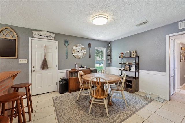 233 Spooner St, Orange, TX 77630 - dining space featuring a textured ceiling, a wainscoted wall, and light tile patterned floors
