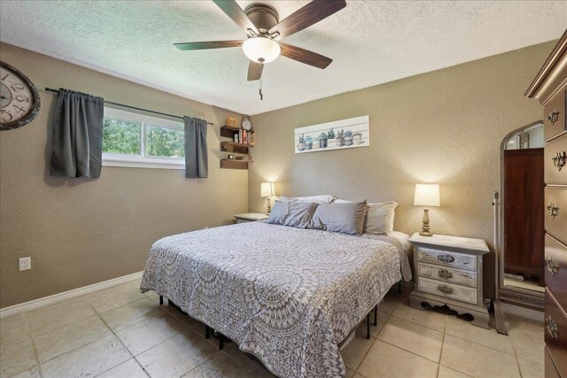 233 Spooner St, Orange, TX 77630 - bedroom featuring light tile patterned floors, a textured wall, a textured ceiling, baseboards, and a ceiling fan