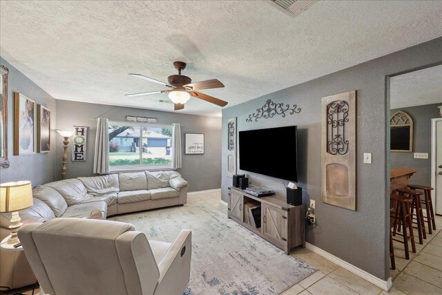 233 Spooner St, Orange, TX 77630 - living area featuring ceiling fan, a textured ceiling, light tile patterned flooring, a textured wall, and baseboards