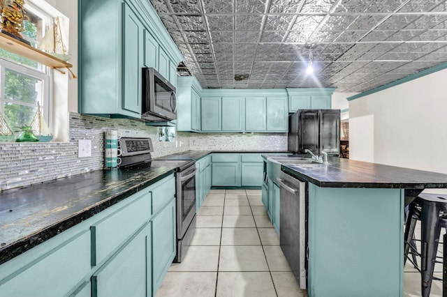 7775 River Rd, Beaumont, TX 77713 - kitchen featuring appliances with stainless steel finishes, dark countertops, backsplash, a kitchen breakfast bar, and an ornate ceiling