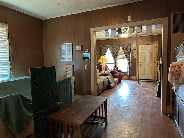 dining space featuring wood-type flooring, ornamental molding, ceiling fan, and wood walls