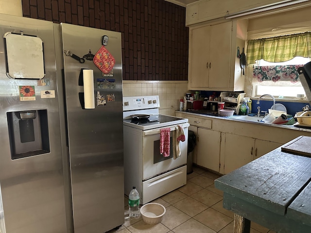 kitchen with sink, stainless steel fridge, backsplash, light tile patterned floors, and electric stove