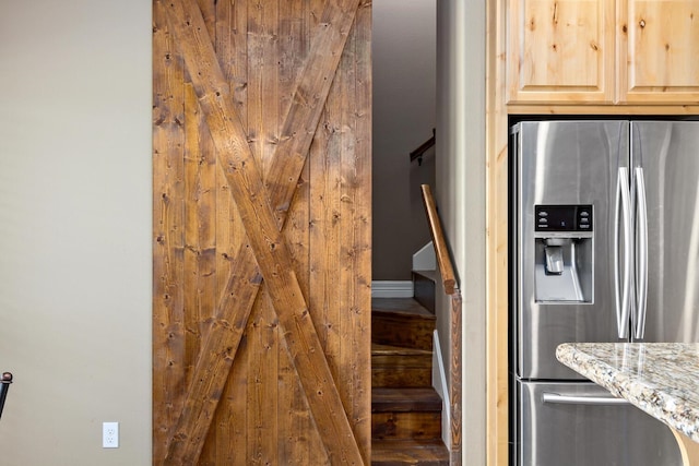 kitchen with light stone countertops, stainless steel fridge with ice dispenser, and light brown cabinets