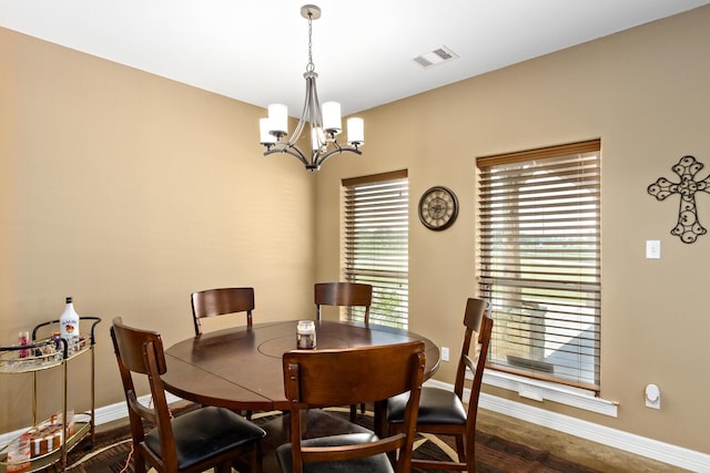 dining area with dark wood-type flooring and an inviting chandelier