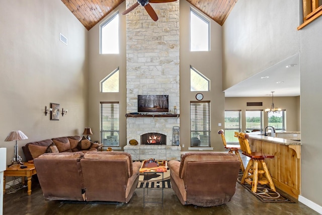 living room featuring ceiling fan with notable chandelier, a towering ceiling, and a fireplace