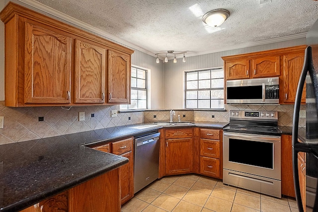 8228A Ponderosa Dr, Silsbee, TX 77656 - kitchen featuring stainless steel appliances, a sink, ornamental molding, brown cabinetry, and decorative backsplash