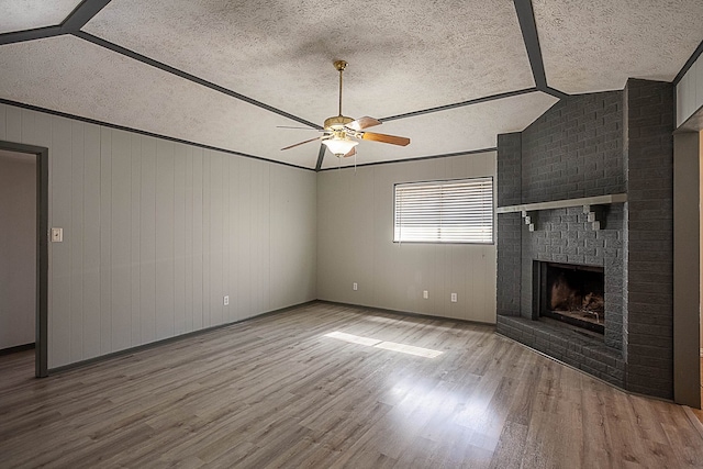 8228A Ponderosa Dr, Silsbee, TX 77656 - unfurnished living room featuring a textured ceiling, a ceiling fan, wood finished floors, a brick fireplace, and vaulted ceiling