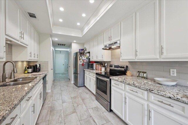 6650 Windwood Ln, Beaumont, TX 77706 - kitchen with stainless steel appliances, under cabinet range hood, a sink, a raised ceiling, and white cabinets