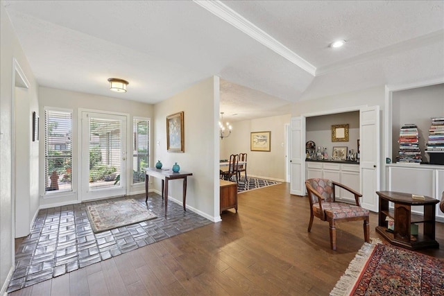 6650 Windwood Ln, Beaumont, TX 77706 - entryway with baseboards, dark wood-style flooring, a textured ceiling, crown molding, and a chandelier