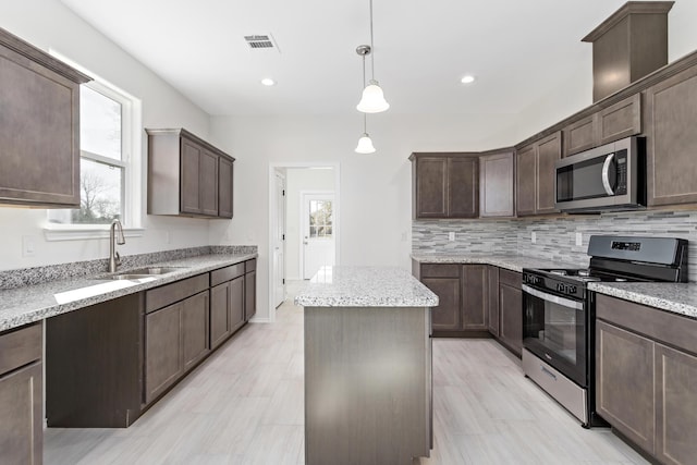 kitchen featuring pendant lighting, a center island, stainless steel appliances, dark brown cabinetry, and sink