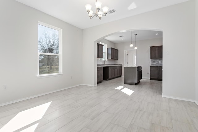 unfurnished living room with a notable chandelier and sink