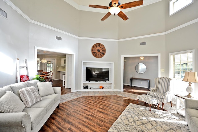 living room with hardwood / wood-style flooring, ceiling fan, and a towering ceiling