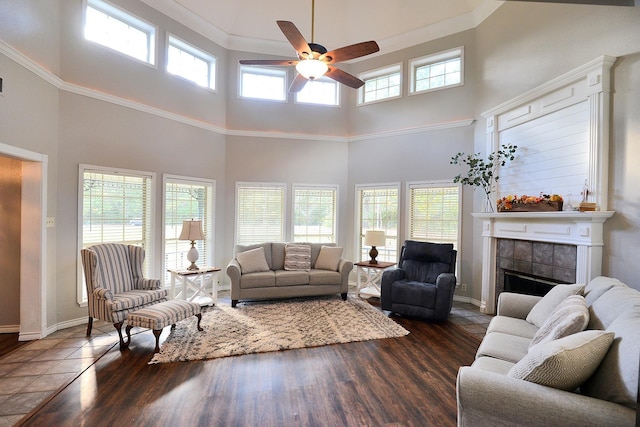 living room featuring ceiling fan, a fireplace, and a towering ceiling