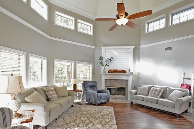 living room featuring a fireplace, a towering ceiling, dark hardwood / wood-style floors, and ceiling fan