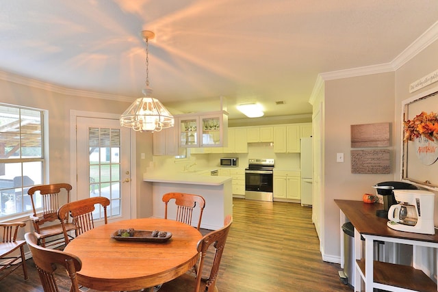 dining room with a notable chandelier, ornamental molding, sink, and dark wood-type flooring