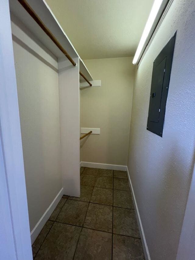 spacious closet featuring electric panel and dark tile patterned floors