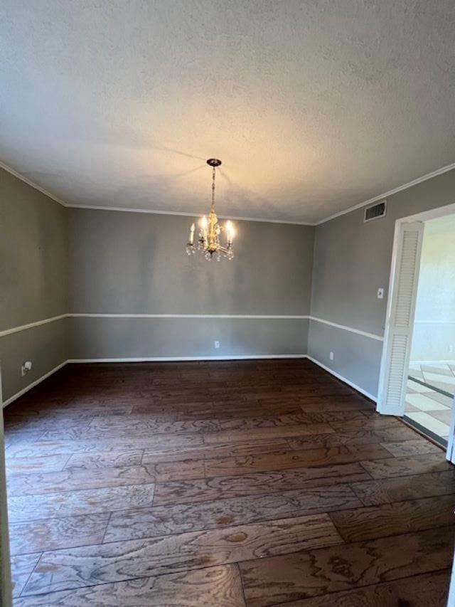 unfurnished room featuring crown molding, dark wood-type flooring, a textured ceiling, and an inviting chandelier