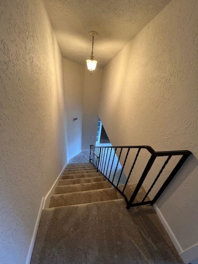 stairs featuring carpet and a textured ceiling