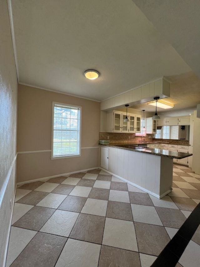 kitchen featuring white cabinetry, kitchen peninsula, hanging light fixtures, and backsplash