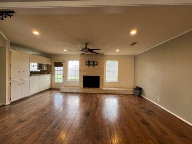 unfurnished living room with a fireplace, dark hardwood / wood-style floors, and ceiling fan