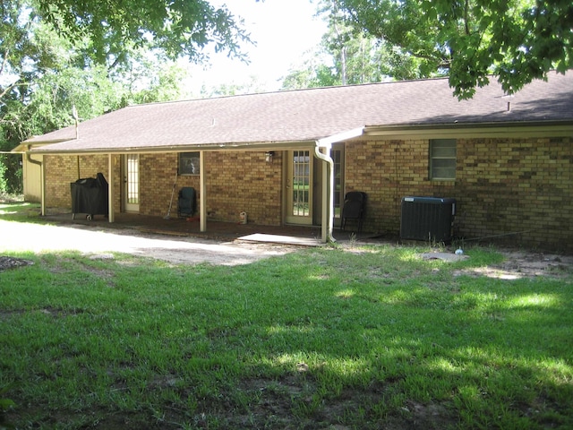 100 Cypress Bnd, Village Mills, TX 77663 - rear view of property featuring a lawn, brick siding, a shingled roof, and a patio