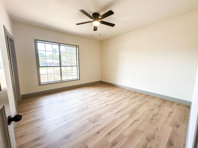 empty room with ceiling fan and light hardwood / wood-style flooring