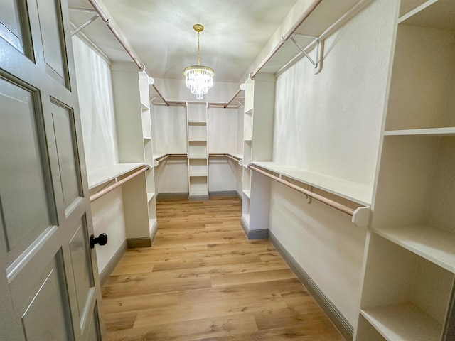 walk in closet featuring light hardwood / wood-style floors and a notable chandelier