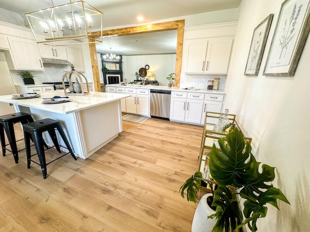 kitchen featuring decorative backsplash, light wood-type flooring, stainless steel dishwasher, decorative light fixtures, and white cabinets