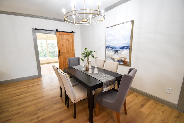 dining space featuring a barn door, hardwood / wood-style flooring, ornamental molding, and a notable chandelier