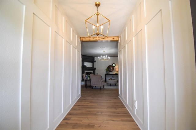 hallway with wood-type flooring and an inviting chandelier