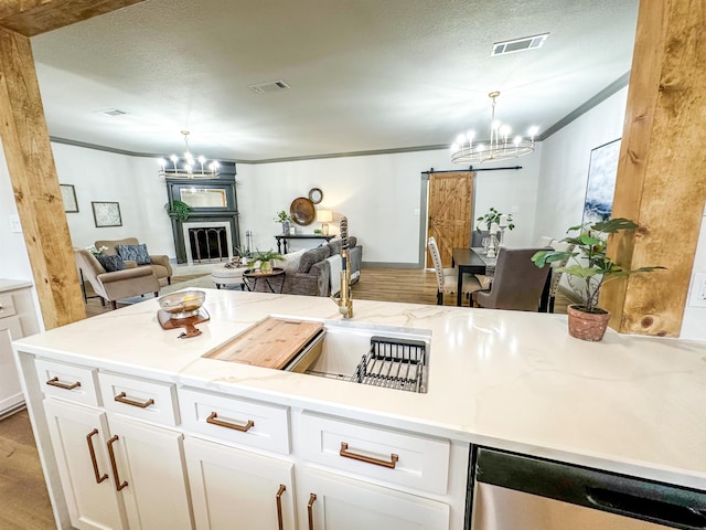 kitchen with hanging light fixtures, wine cooler, a barn door, a fireplace, and white cabinetry