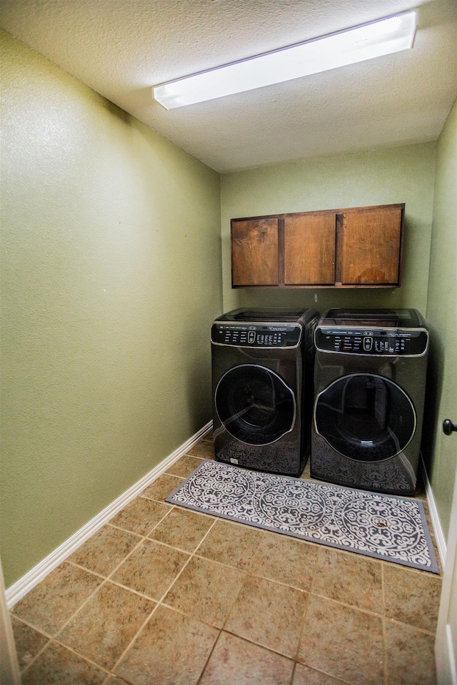 laundry area featuring cabinets, tile patterned flooring, washing machine and clothes dryer, and a textured ceiling