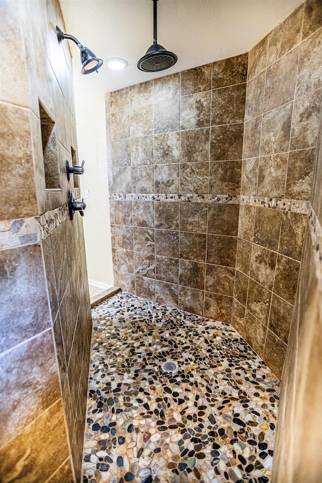 bathroom with a textured ceiling and tiled shower